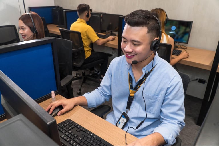 A group of Select VoiceCom customer service representatives taking calls in a Philippine call center office.