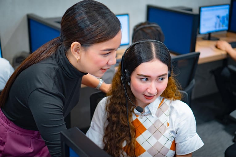 A female team leader helping a female call center agent from Select VoiceCom during work hours inside a Philippine call center office.