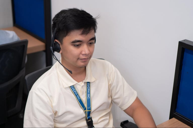 A male call center agent from Select VoiceCom answering a customer inquiry in a Philippine call center office.