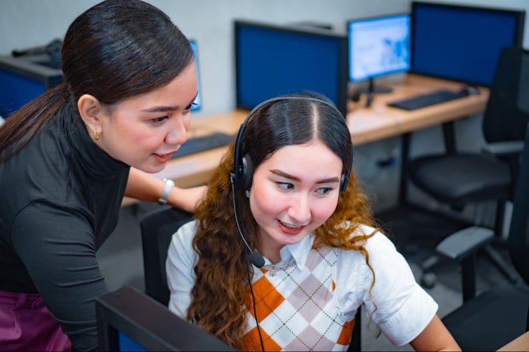 A female team leader assisting a female call center agent in Select VoiceCom's office.