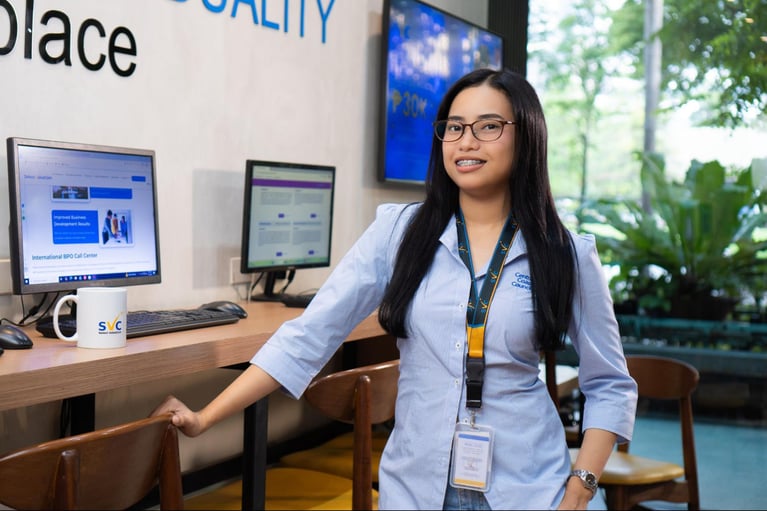 A female call centre agent from Select VoiceCom standing/posing inside the call centre office in the Philippines.