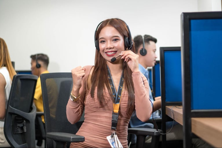 A Select VoiceCom female call center representative, with other agents in the background, working in a Philippine call center office.