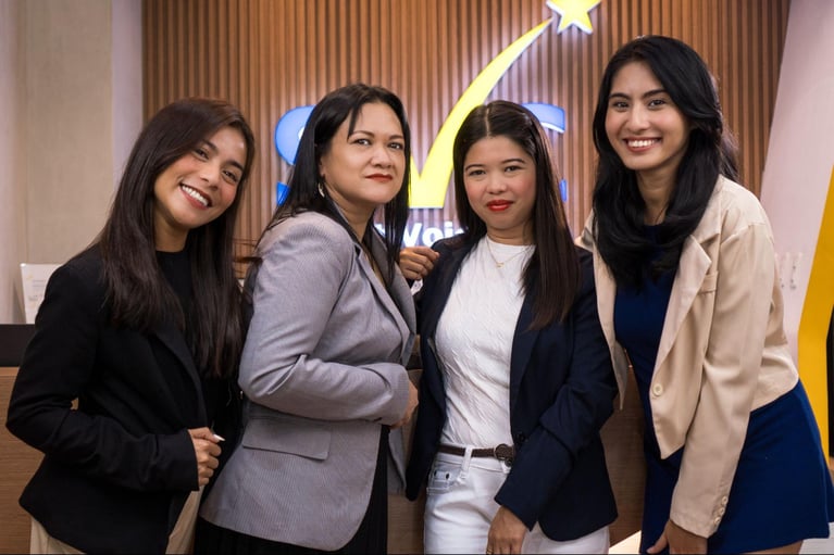 Four female Select VoiceCom employees in a frame inside a Philippine call center office.
