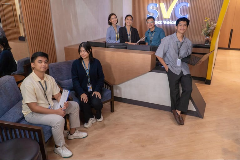 A group of Select VoiceCom employees pose for a photo op in a Philippine call center office.